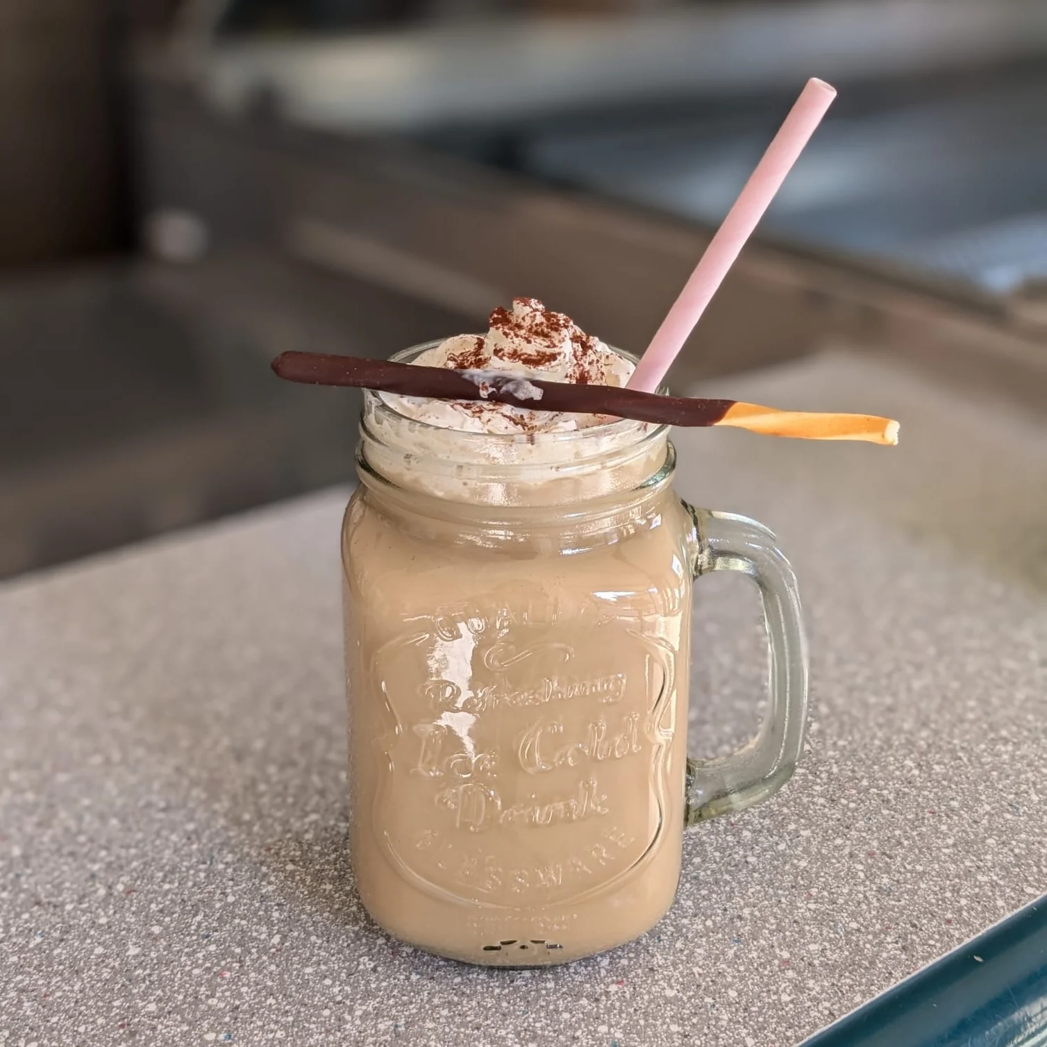 Iced latte phone photo with cluttered cafe counter background